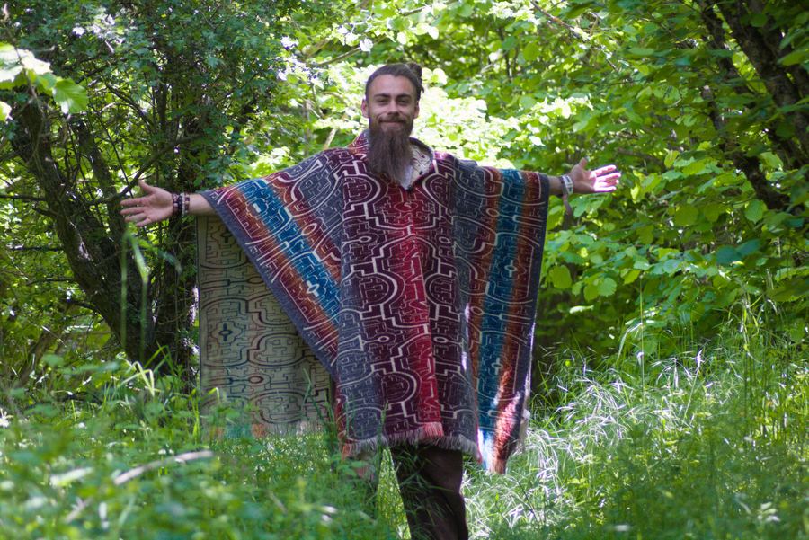 Philipp Meier steht mit ausgebreiteten Armen in einem sommergrünen Wald