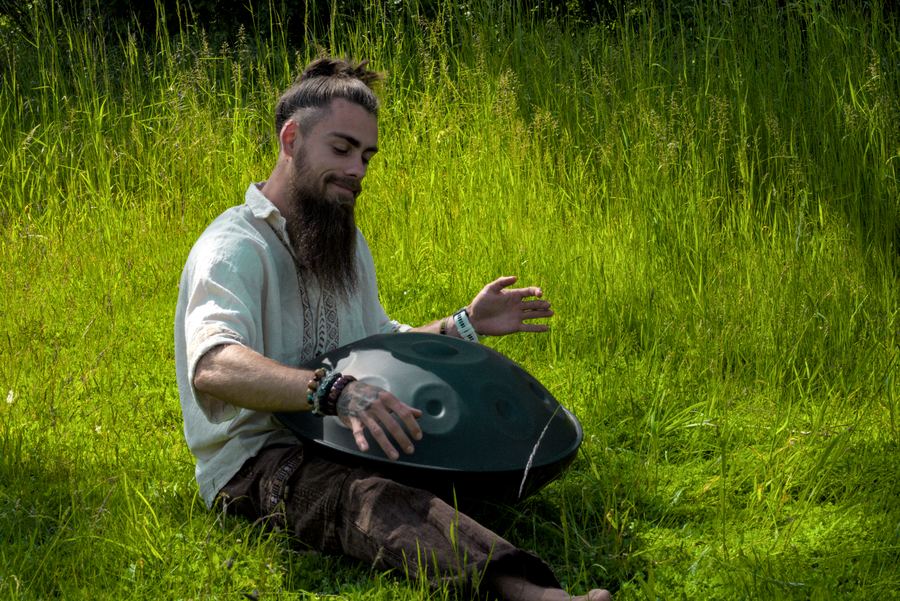 Philipp Meier spielt eine Handpan im hohen Gras einer Wiese